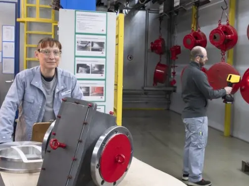 Employees working on safety equipment in an industrial setting, highlighting compliance and excellence in safety and environment